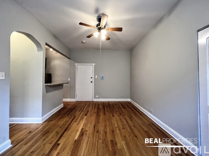 A room with a ceiling fan and wooden flooring.