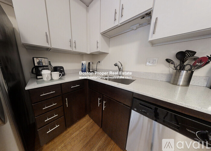 A kitchen with white cabinets and a wooden floor.