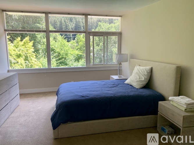 A bedroom with a large bed and a window overlooking a forest.