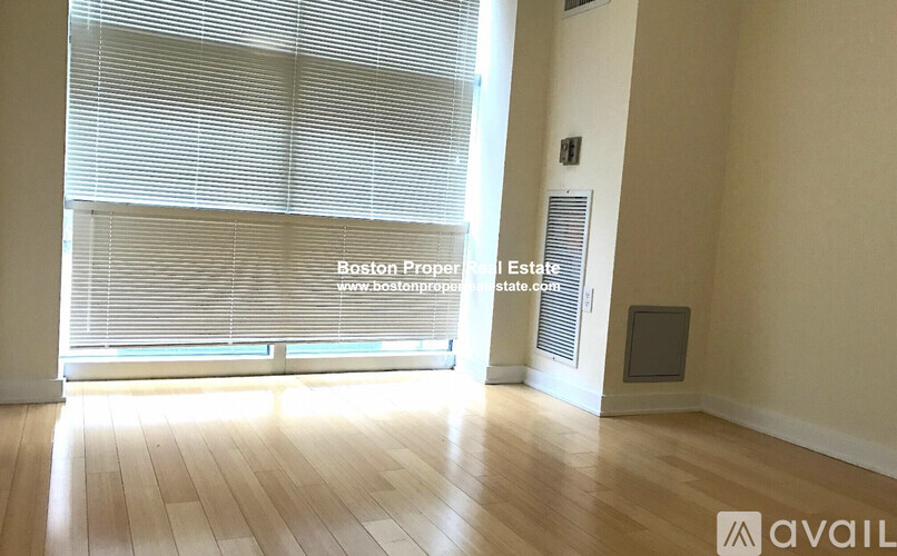A room with wooden floors and a window covered with blinds.