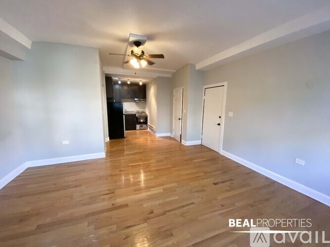 A spacious room with wooden flooring and a ceiling fan.