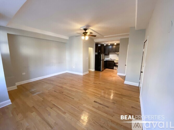 A spacious room with wooden flooring and a ceiling fan.