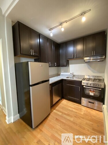 A kitchen with a refrigerator, oven, and sink.