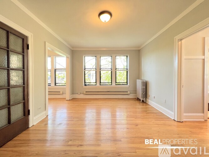 A spacious room with wooden floors and a large window.