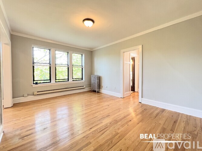 A room with wooden floors and a window with a view of trees.