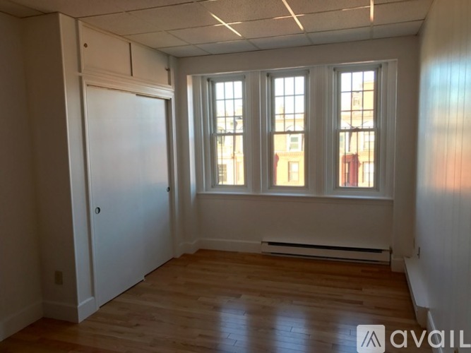 A room with wooden floors and a window with a view of buildings outside.