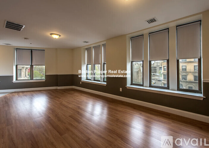 A room with wooden flooring and large windows.