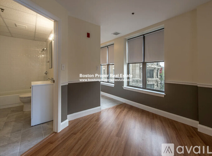 A bathroom with wooden floors and a window with blinds.