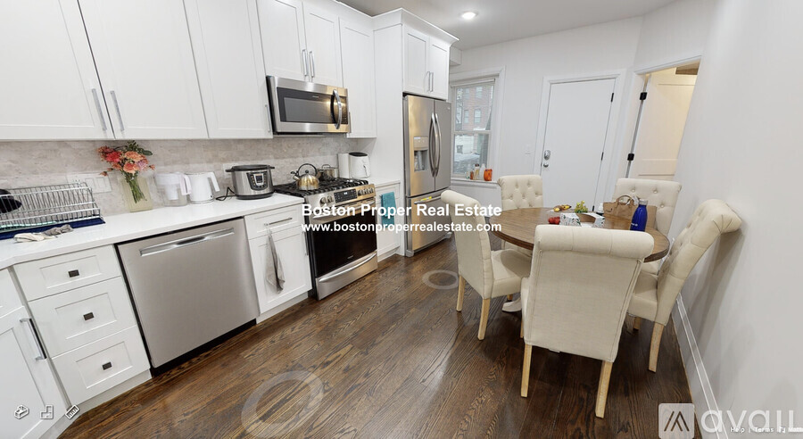 A kitchen with white cabinets and a dining table with chairs.