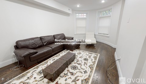 A living room with a brown couch and a floral rug.