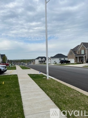 A suburban street with houses on both sides and a sidewalk in the foreground.