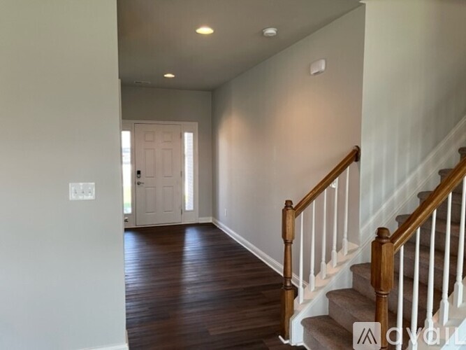 A hallway with a staircase and a white door.