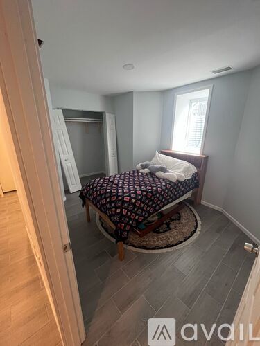 A bedroom with a bed and a rug in the middle of the room.