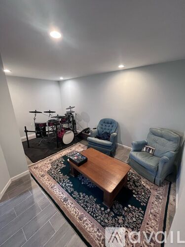 A living room with a drum set and two chairs.