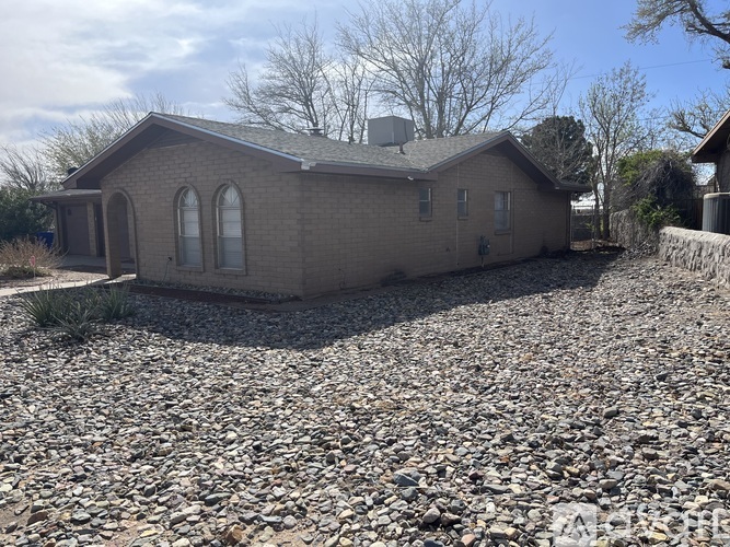 A house with a grey roof and a gravel driveway in front.