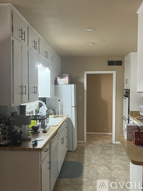 A kitchen with white cabinets and a refrigerator.