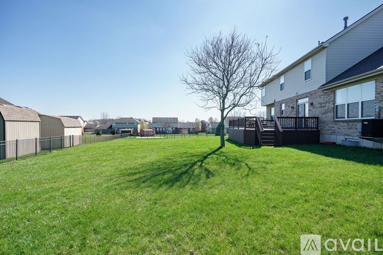 A grassy field with a tree and houses in the background.