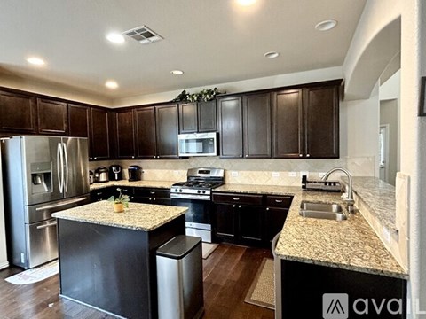 A kitchen with dark wood cabinets and granite countertops.