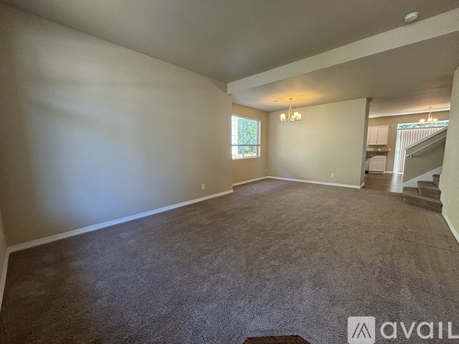 A spacious room with a carpeted floor and a window.