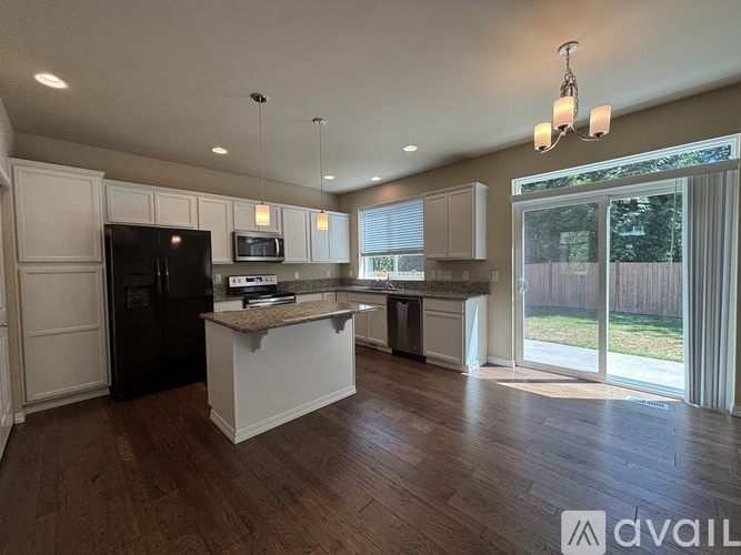A kitchen with a granite countertop and a black refrigerator.