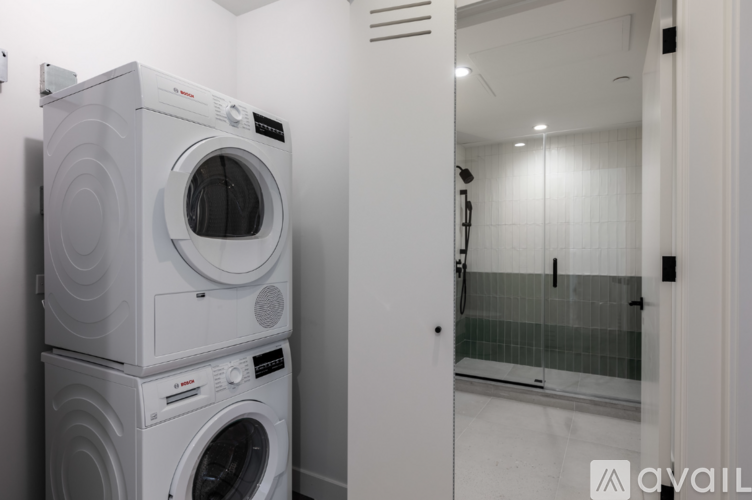 A stack of white front loading washing machines in a laundry room.