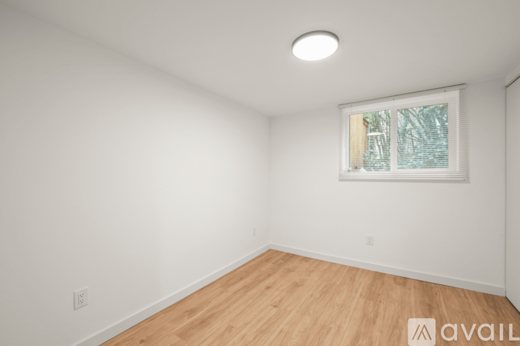 A room with wooden flooring and a window with blinds.