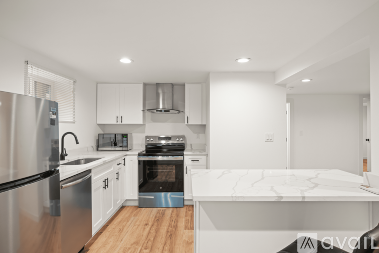 A modern kitchen with a white marble island and stainless steel appliances.