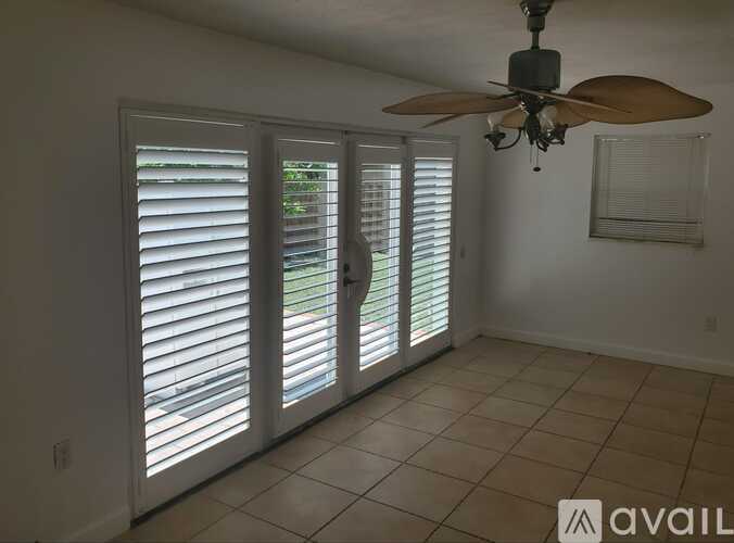 A room with a ceiling fan and sliding glass doors.
