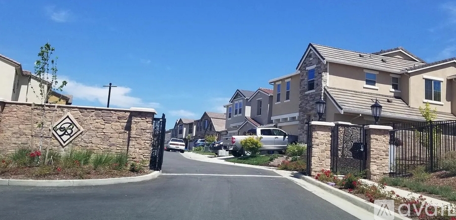 A gated entrance to a residential street with houses on either side.