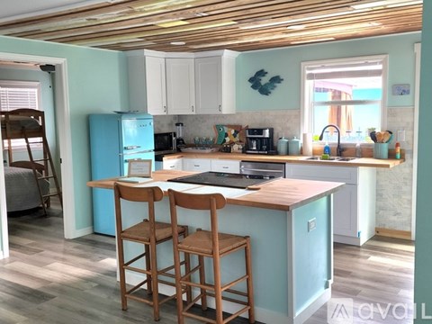 A kitchen with a blue refrigerator and wooden bar stools.