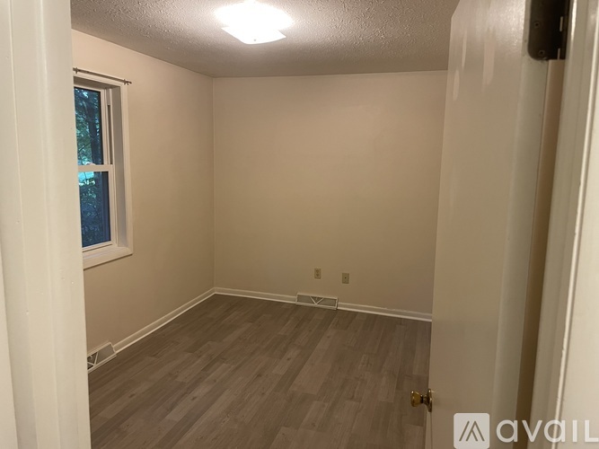 A room with a window and wooden flooring.
