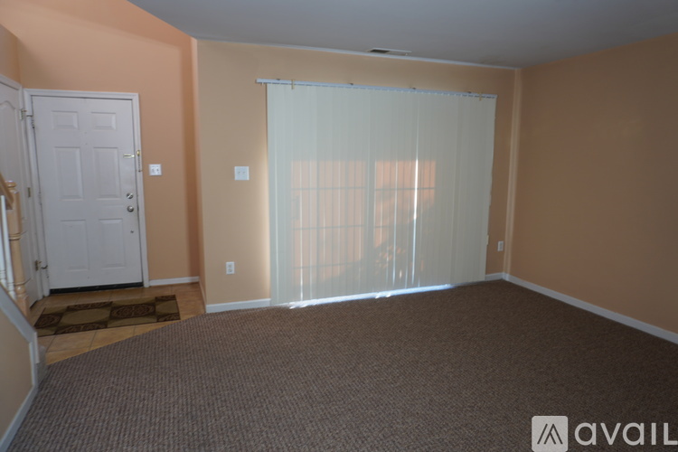 A room with a carpeted floor and a sliding glass door.