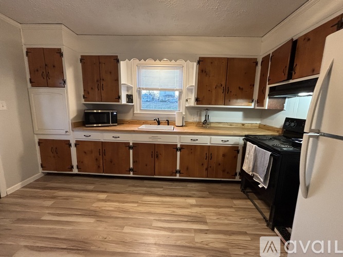 A kitchen with wooden cabinets and a black fridge.