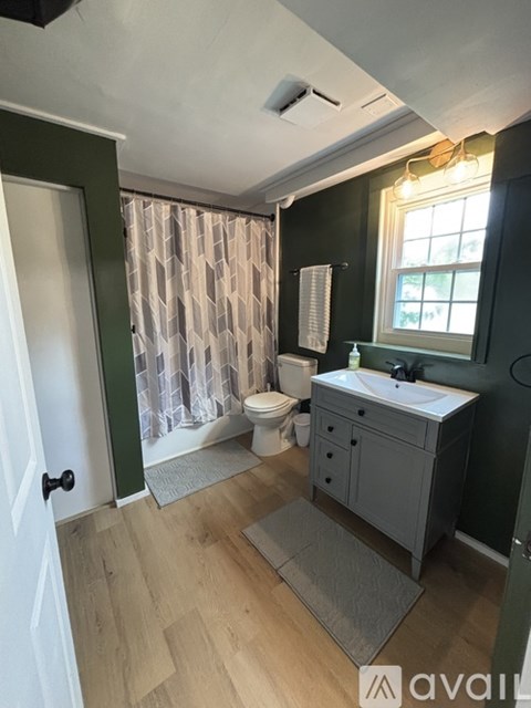 A room with wooden flooring and a window with curtains.