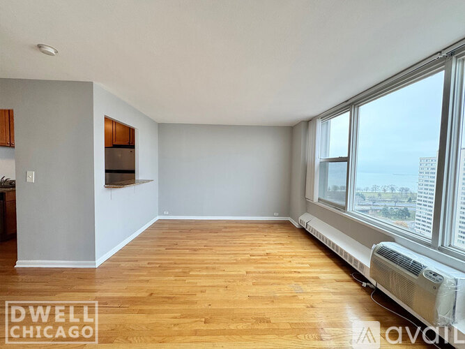 A spacious room with wooden floors and a large window overlooking a cityscape.