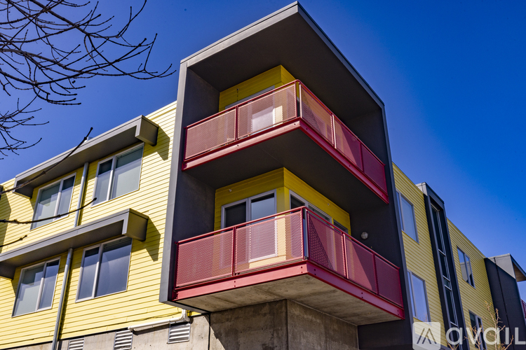 A modern building with a yellow and red exterior and balconies.