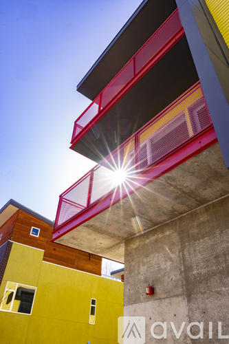 A bright sun shines through a gap in a red structure.