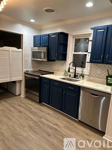 A kitchen with dark blue cabinets and a stainless steel dishwasher.