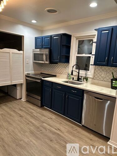A kitchen with dark blue cabinets and a stainless steel dishwasher.