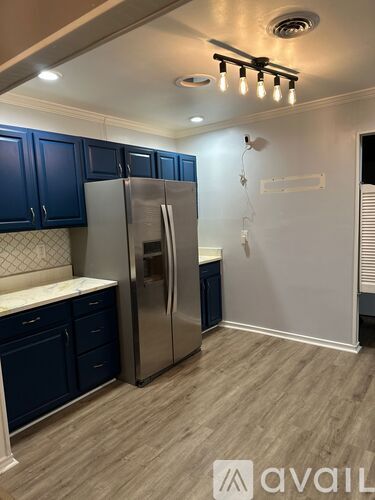 A kitchen with a stainless steel refrigerator and dark blue cabinets.