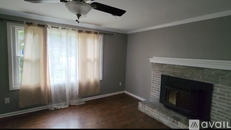 A living room with a fireplace and a ceiling fan.