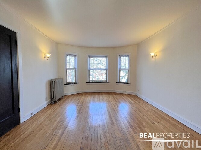 A room with wooden floors and three windows.
