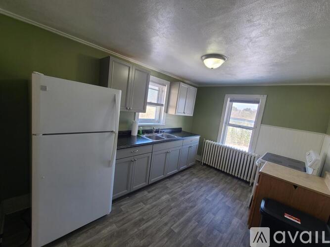 A kitchen with a white refrigerator and wooden floors.