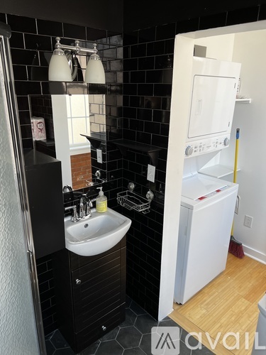 A bathroom with a white sink and a white fridge.