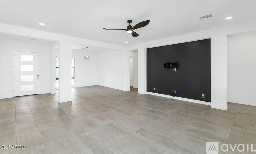 A spacious room with a ceiling fan and a flat screen TV mounted on the wall.
