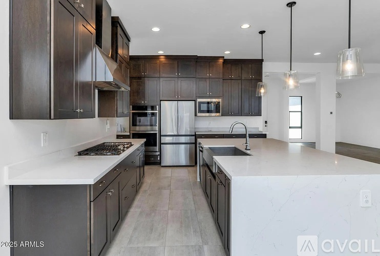 A modern kitchen with dark wood cabinets and stainless steel appliances.