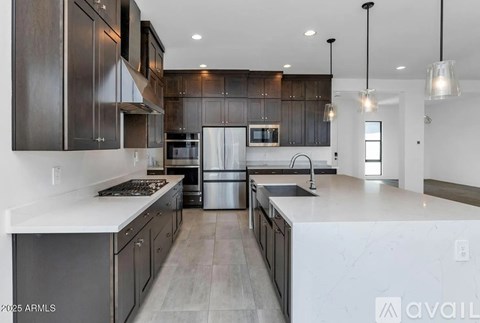 A modern kitchen with dark wood cabinets and stainless steel appliances.