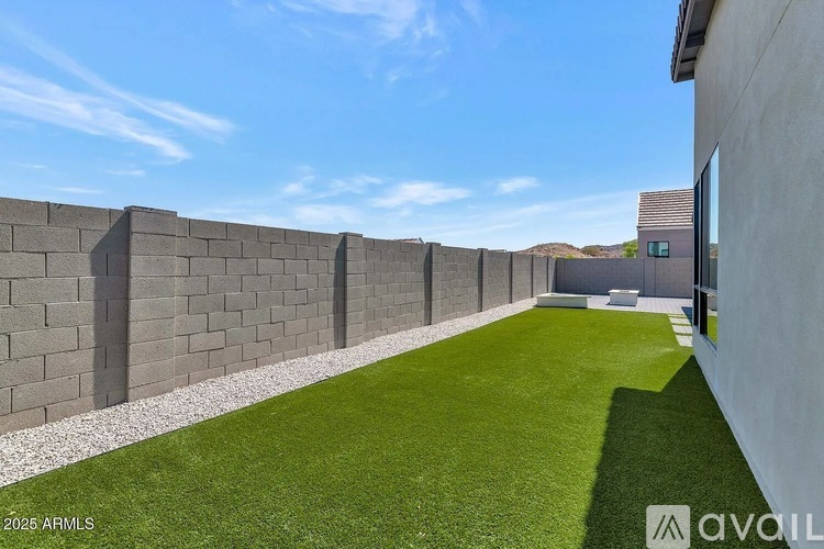A wall of grey blocks separates a green lawn from a building.