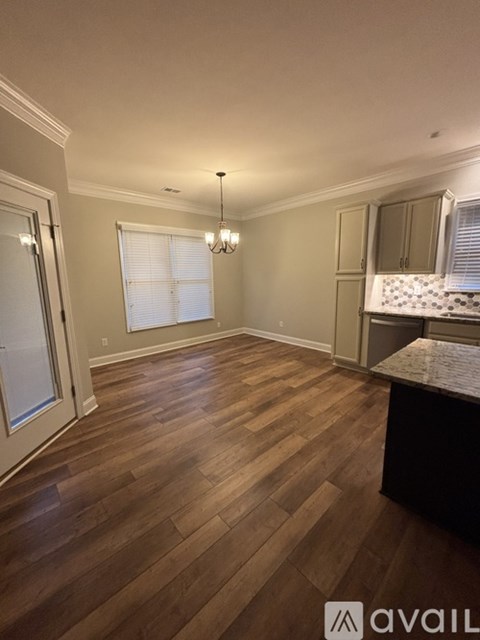 A room with wooden flooring and a kitchen area with a counter.