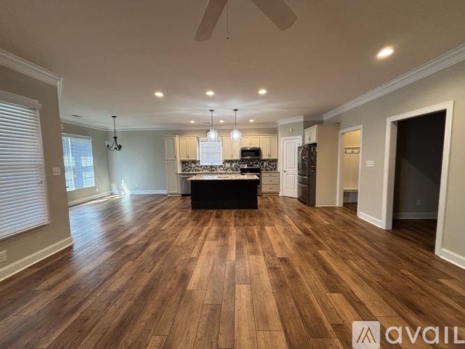 A spacious room with wooden flooring and a ceiling fan.